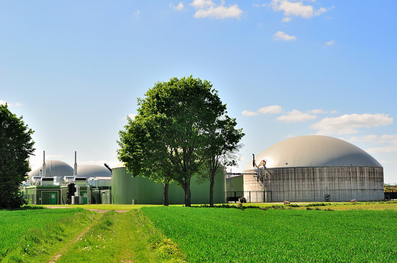 biogas plant in field with trees surrounded by grass